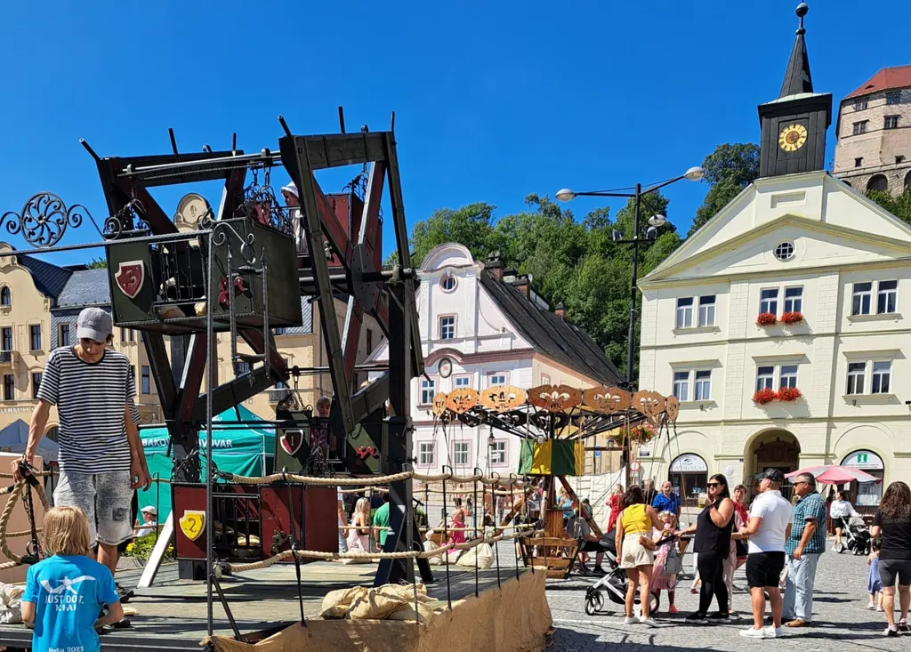 Ruské kolo a starodávný kolotoč na náměstí, v pozadí radnice s věží